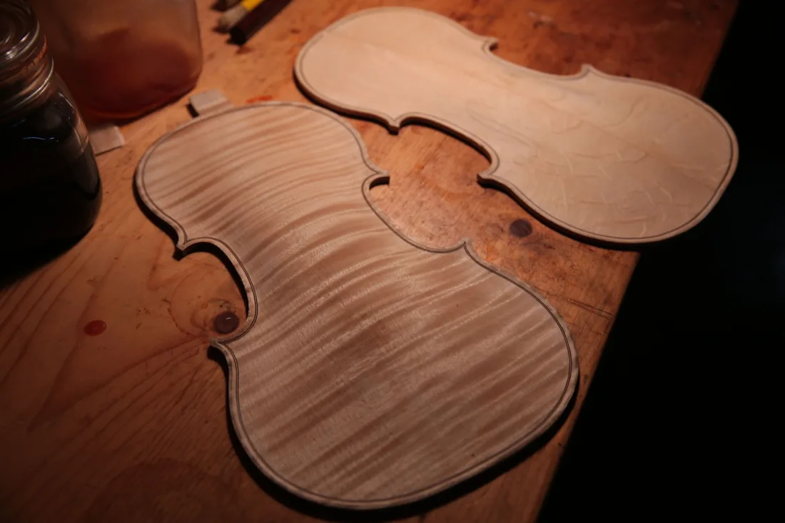 Tapa y fondo de violín sin terminar, en abeto y arce, sobre el banco de un taller de luthería
